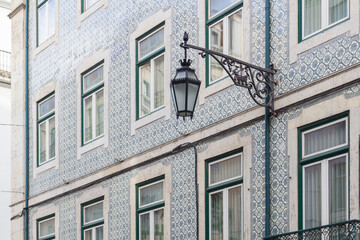 Ancient Portuguese building, covered with blue patterned azulejo tile and with a wrought-iron lantern on the wall