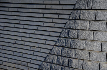 the combination of a smooth cut stone wall in longitudinal strips follows the arch of rough granite...