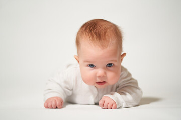 portrait of an infant lying with angry emotion on a white background