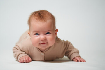 Fototapeta premium Portrait of an infant learning to crawl on a white background