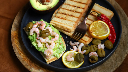 Fototapeta na wymiar Guacamole toast with avocado, shrimp and olives. Healthy snack. Keto.