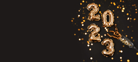 Banner of foil gold air balloons in the form of numbers 2023 on black background. New year and...