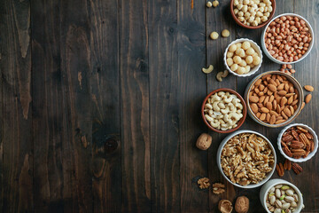 Obraz na płótnie Canvas Nuts variety in the bowls - cashew, hazelnut, macadamia, pistachio, almond, walnut, peanut, pecan