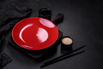 Empty plate with wooden sticks for Asian food on a dark concrete background