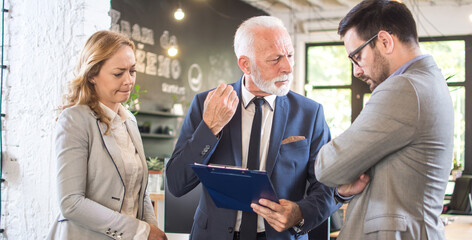 Senior businessman arguing with his younger colleague about document mistake on meeting in office.