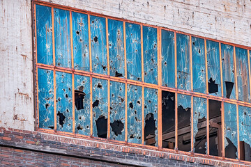 Building in industrial zone with windows broken from stones, bullets and shards. The concept of...