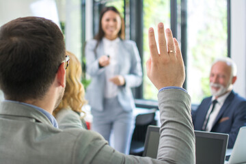 Business people raising hand up at a conference to answer a question.