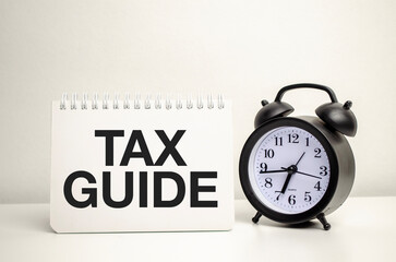 TAX GUIDE words with calculator and clock with notebook