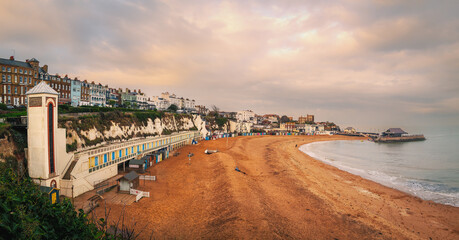 Panoramic image of Viking Bay, Broadstairs, UK on a mild winter day. The elevator shaft to the beach and the row of beach huts can be seen along with the pier. - 550694767