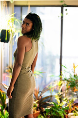 Black Woman with green dreadlocks in green dress surrounded by plants