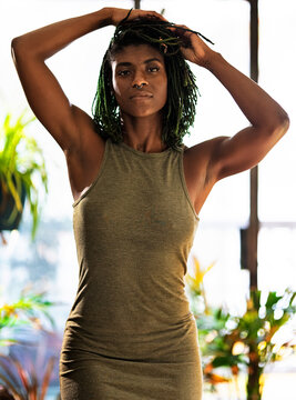 Black Woman with green dreadlocks in green dress surrounded by plants