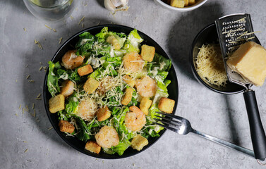 Cesar salad with grilled shrimp, croutons and parmesan cheese on grey marble table 