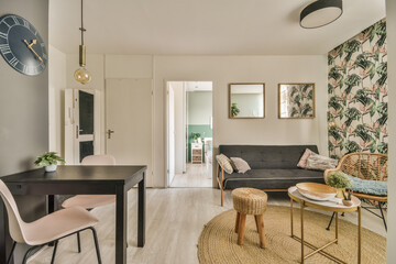 Table with chairs and flowers located near lounge area and kitchen in spacious room of contemporary...