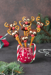 Cake pops Santa reindeers from marshmallows, sweet straw and chocolate on brown background, Idea Christmas treats for kids