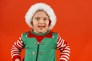 Happy child with Down syndrome in Christmas scarf having fun and laughing in studio. Christmas...