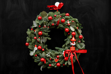 Natural Christmas fir wreath with red balls and red ribbon on dark background