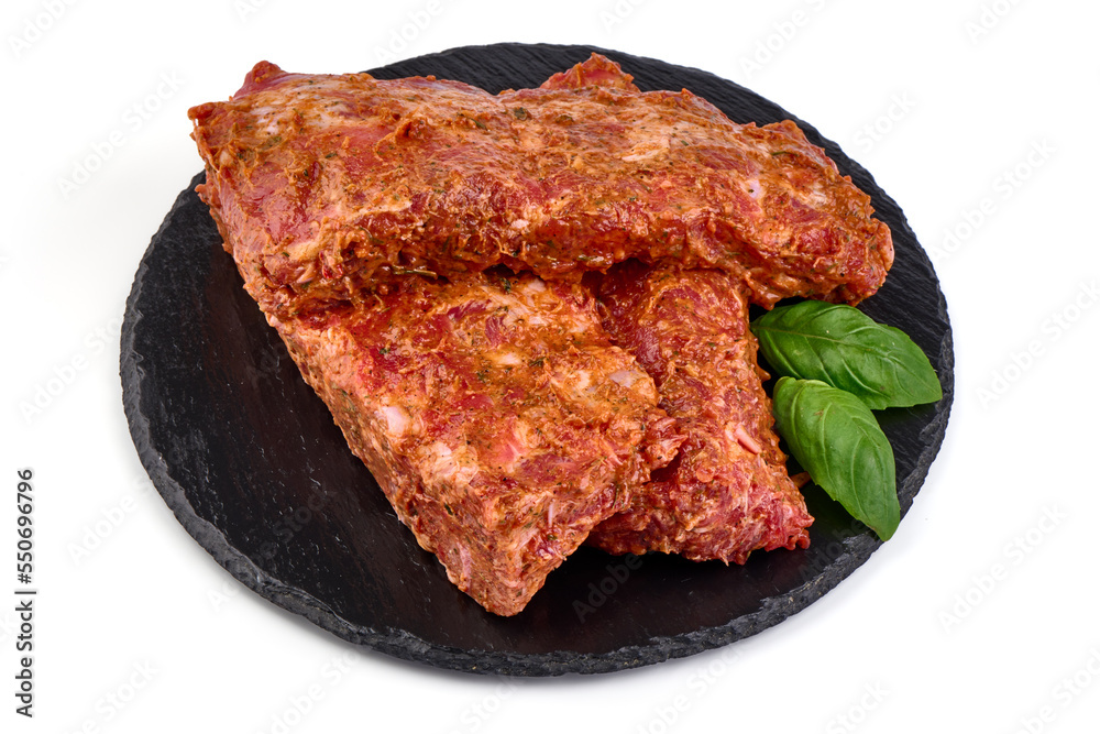 Wall mural Raw marinated pork ribs on black stone plate ready for cooking, isolated on white background.