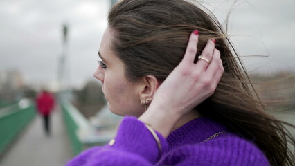 Young woman feeling the wind, girl standing outside releasing hair blowing wind