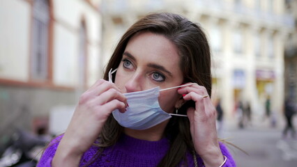 Young woman putting covid-19 face mask. Person wearing surgicak mask