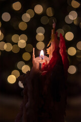 burning candle with melting wax and christmas light bokeh