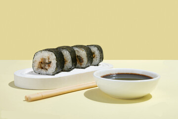 Asian culture, Japanese hosomaki (sushi, rolls) with eel on a yellow background. Oriental culinary, eastern cooking.