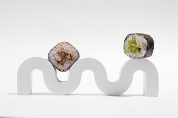 Japanese hosomaki (sushi, rolls) with eel on a white plaster stand on a white plain background.