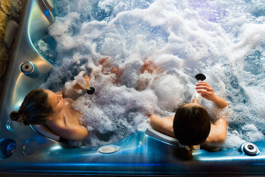Shot from above of a young couple of female sitting together in a hot tub