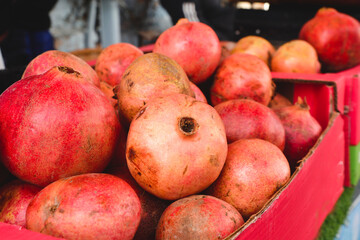group of ripe pomegranates in boxes for sell in a stall Group of pomegranates on display at local farmers' market. Pomegranate closeup, background.