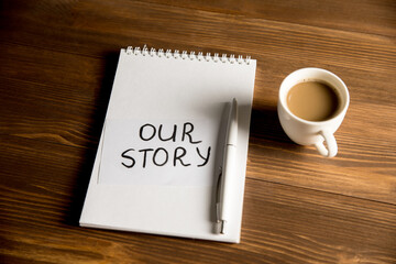 The inscription on the notebook Our story and a cup of coffee