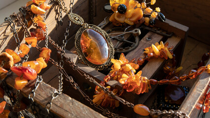 Different Baltic amber jewelry lying on an old wood clockwork. Natural amber necklaces and transparent amber pendant with inclusion.