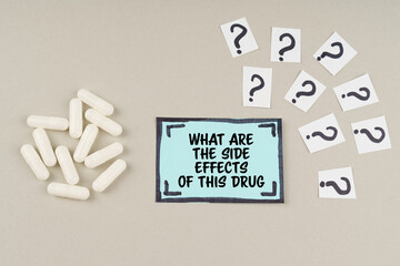 On a gray surface there are question marks and a sticker with the inscription - What are the side effects of this drug