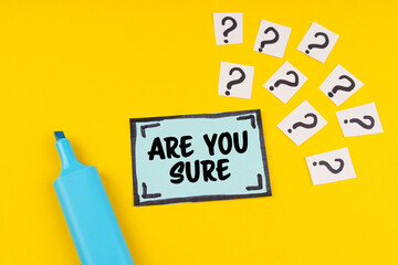 On the yellow surface is a marker, question marks and a sticker with the inscription - ARE YOU SURE