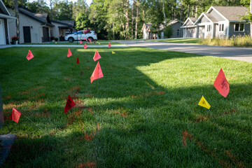 Warning flags on the green grass of a residential lawn, used to prevent injury when digging for...