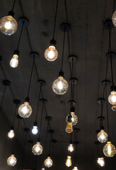 Light bulbs of different sizes and shapes hanging from the ceiling on black long cords