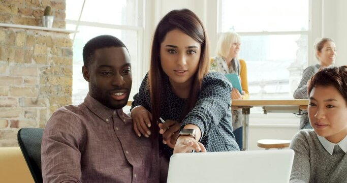 Diversity team, laptop and mentor teaching onboarding staff new software, system or program for design editing. Startup small business, teamwork or collaboration of black man, asian woman and manager