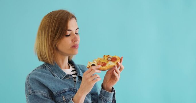 young woman eating pizza slice and looking delighted