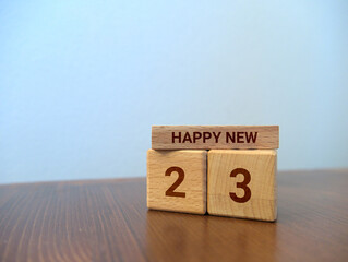Wooden bricks with engraved message: "HAPPY NEW 23" standing on a desk	