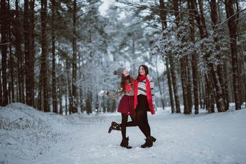 Fototapeta na wymiar Close up fashion portrait of two sisters hugs and having fun in winter time forest, wearing sweaters and scarfs,best friends couple outdoors, snowy weather