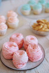 A table with lots of cupcake cakes, marshmallows in pink and blue shades, shortbread cookies. Table setting for gender party parties