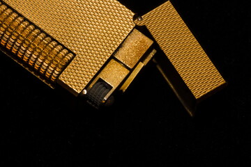 Close-up image of a vintage golden lighter on a black background
