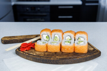 Japanese Philadelphia rolls on a wooden cutting board on a table in the kitchen
