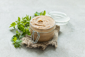 Vegan appetizer. Bean mushroom champignon pate in a glass jar on a linen napkin. Light gray background. Rustic style