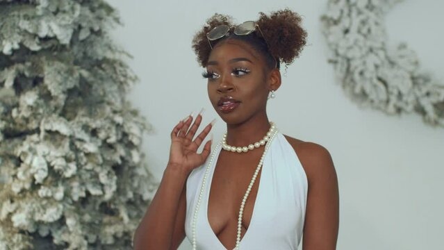 Woman standing in front of white flocked Christmas trees in backless dress turns around 