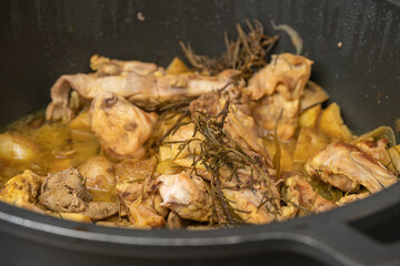 Rabbit meat cooking in a big pan on a kitchen indoor