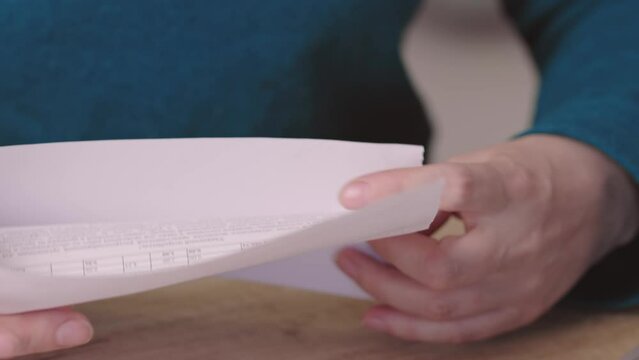 close-up female hands pull out paper envelope utility bill paper letter bank documents. caucasian woman hands opening paper letter post invoice tax forms. tear paper envelope concept