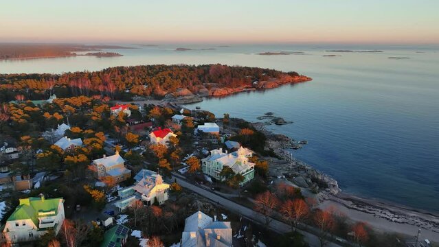 Aerial view overlooking traditional seaside villas in Hanko, spring sunset in Finland - reverse, drone shot