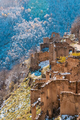 Abandoned ghost town of Gamsutl, Dagestan, Russia. Ruined houses on the backdrop of snow-capped mountains. Stone walls of houses on the hills. Historic quarter at the top of the mountain