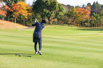 芝生が綺麗なゴルフ場とプレーをする女性