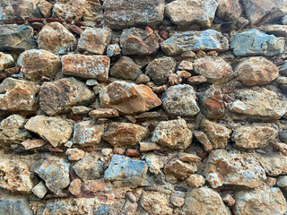 Background, texture, stone wall of round stones cobblestones bricks natural surface natural sharp convex rough stone cobblestone with cracks