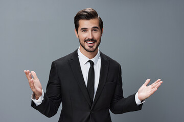 Business man has his hands up and is smiling with his teeth open in a business suit on a gray background portrait